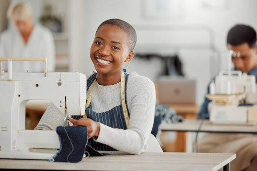 A woman sews a garment using a sewing machine at a sewing school for adults.