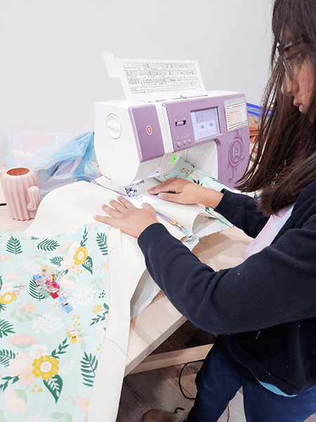 Girl using a sewing machine to sew a dress